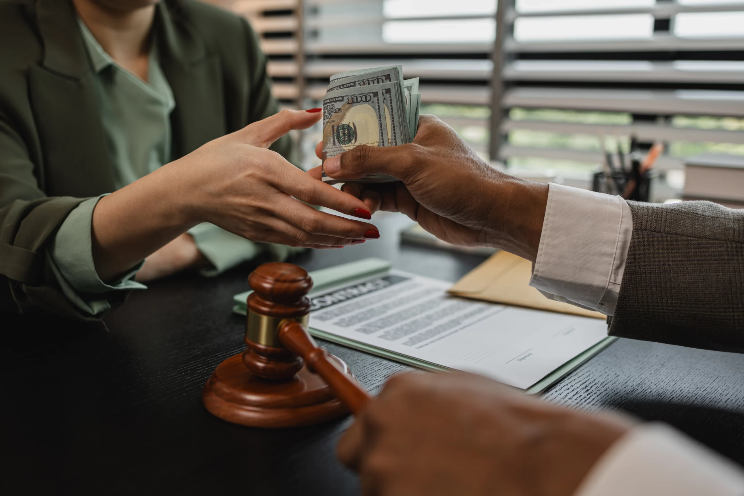 Hands exchanging U.S. dollars over legal documents and gavel, symbolizing a wage garnishment or legal payment in Tennessee.