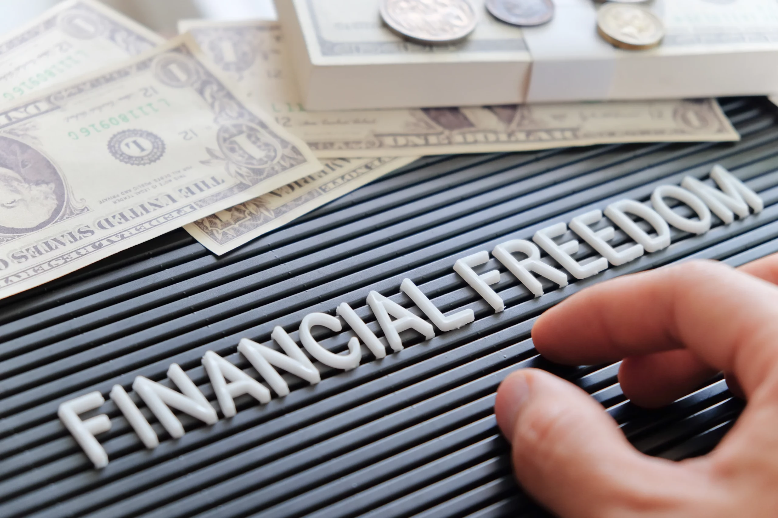 Hand arranging letters spelling “Financial Freedom” with U.S. bills and coins, illustrating overcoming payday loan debt and seeking bankruptcy relief and financial stability in Tennessee.