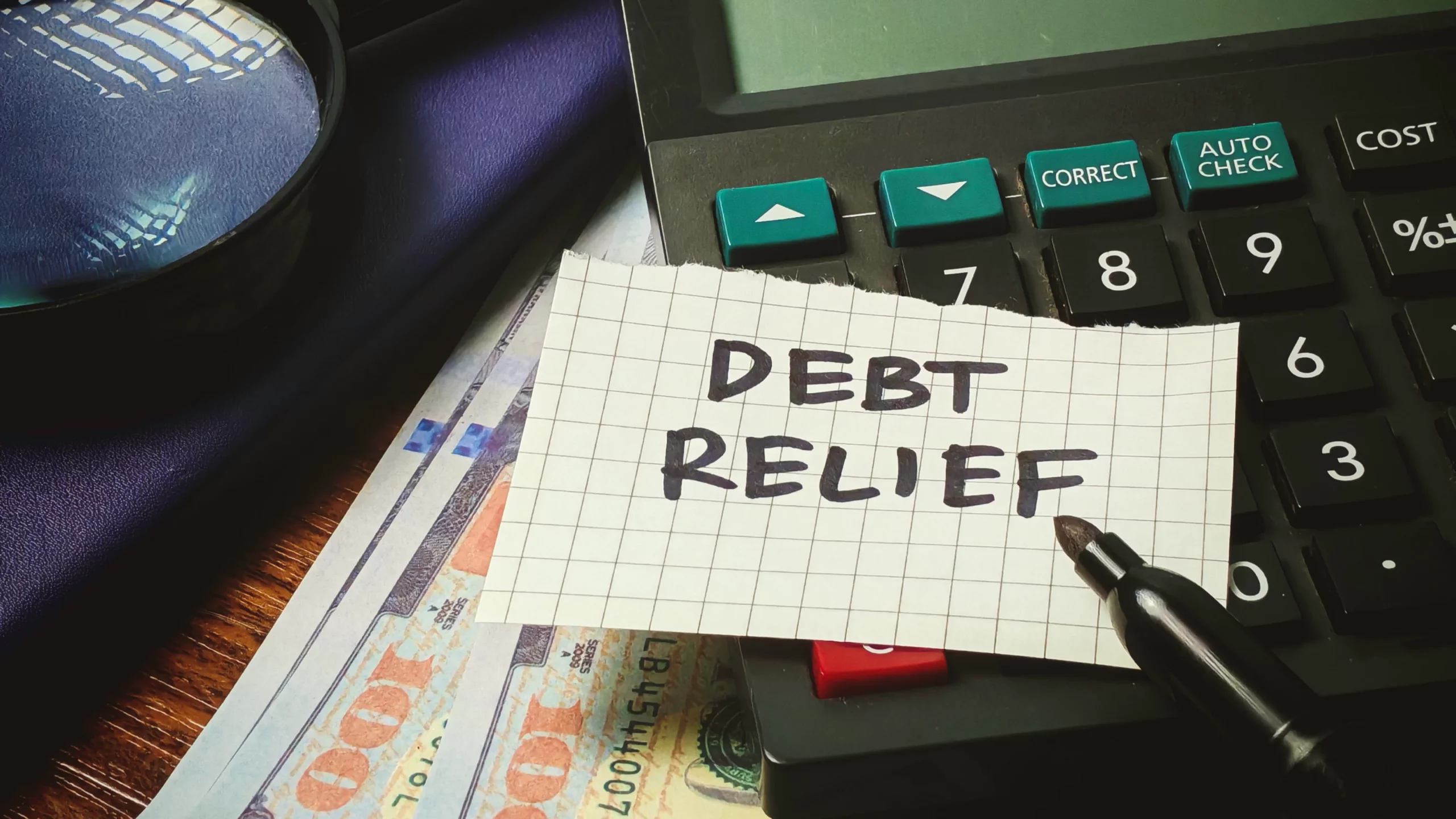 Calculator with note reading “Debt Relief” on U.S. currency and pen, illustrating financial planning and how bankruptcy can stop debt lawsuits and provide relief from creditor actions in Tennessee.