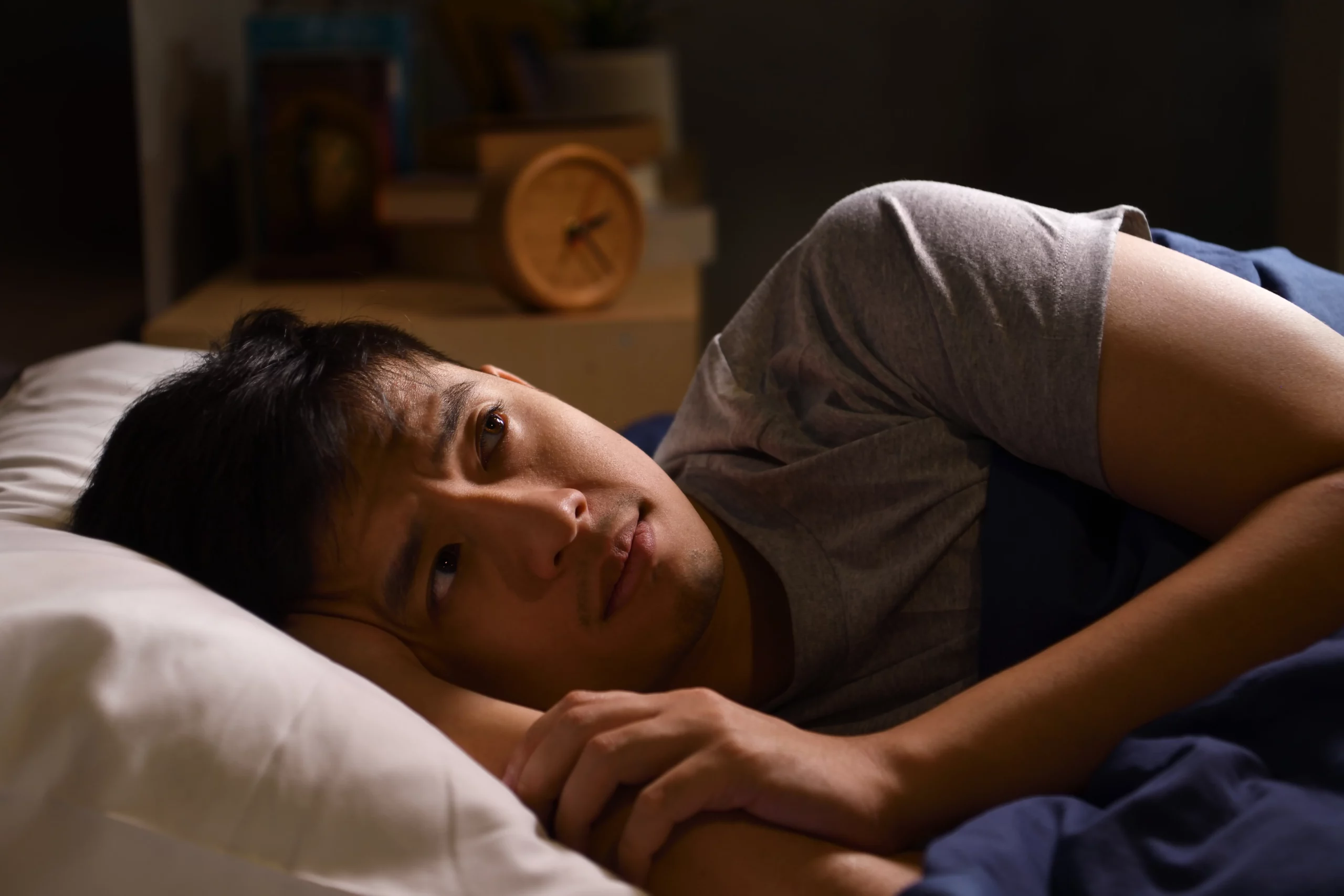Man lying awake in bed looking worried, symbolizing anxiety about losing a security deposit when filing bankruptcy.