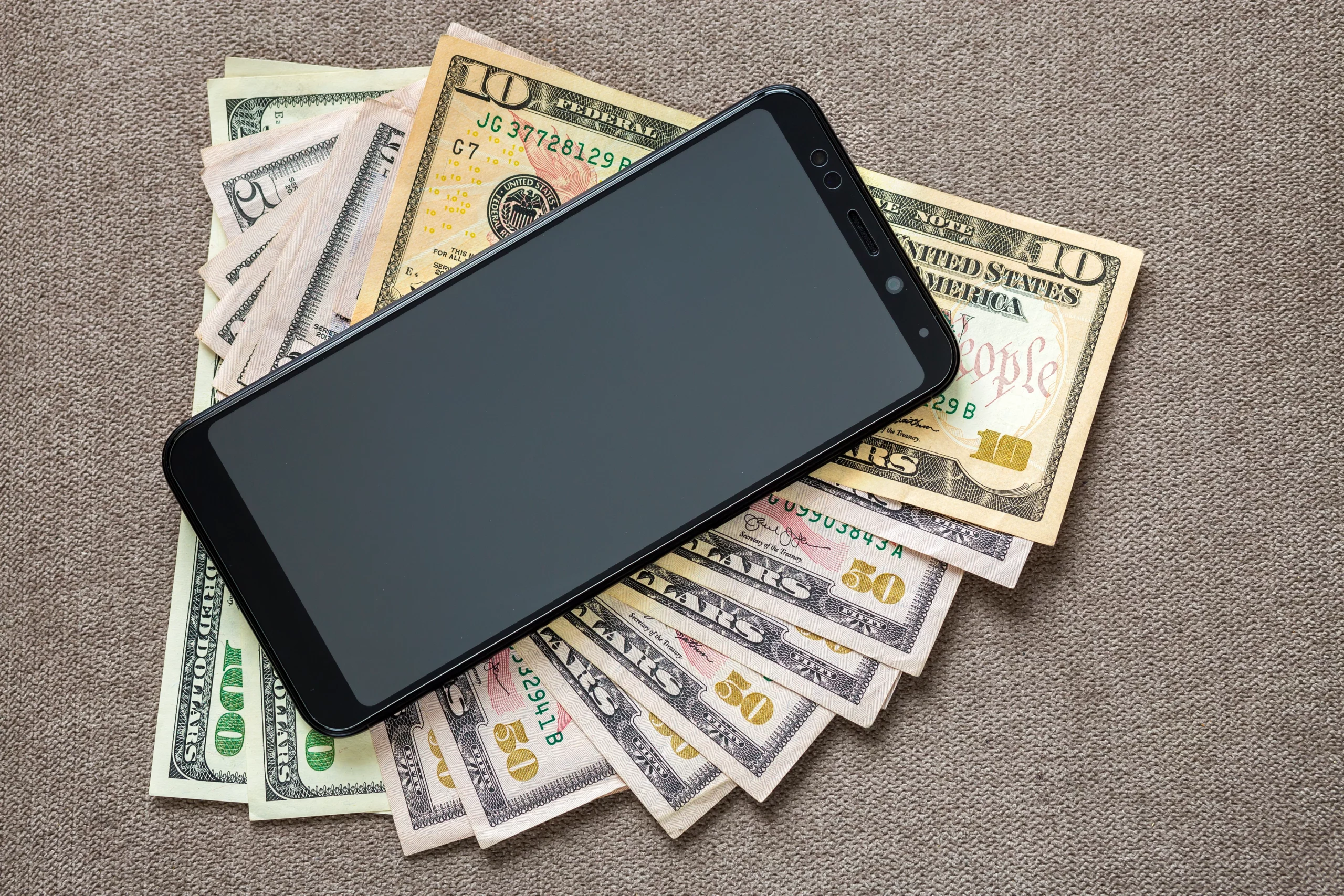 Smartphone placed on US dollar bills symbolizing digital payments and Cash App usage before filing for bankruptcy and managing finances.