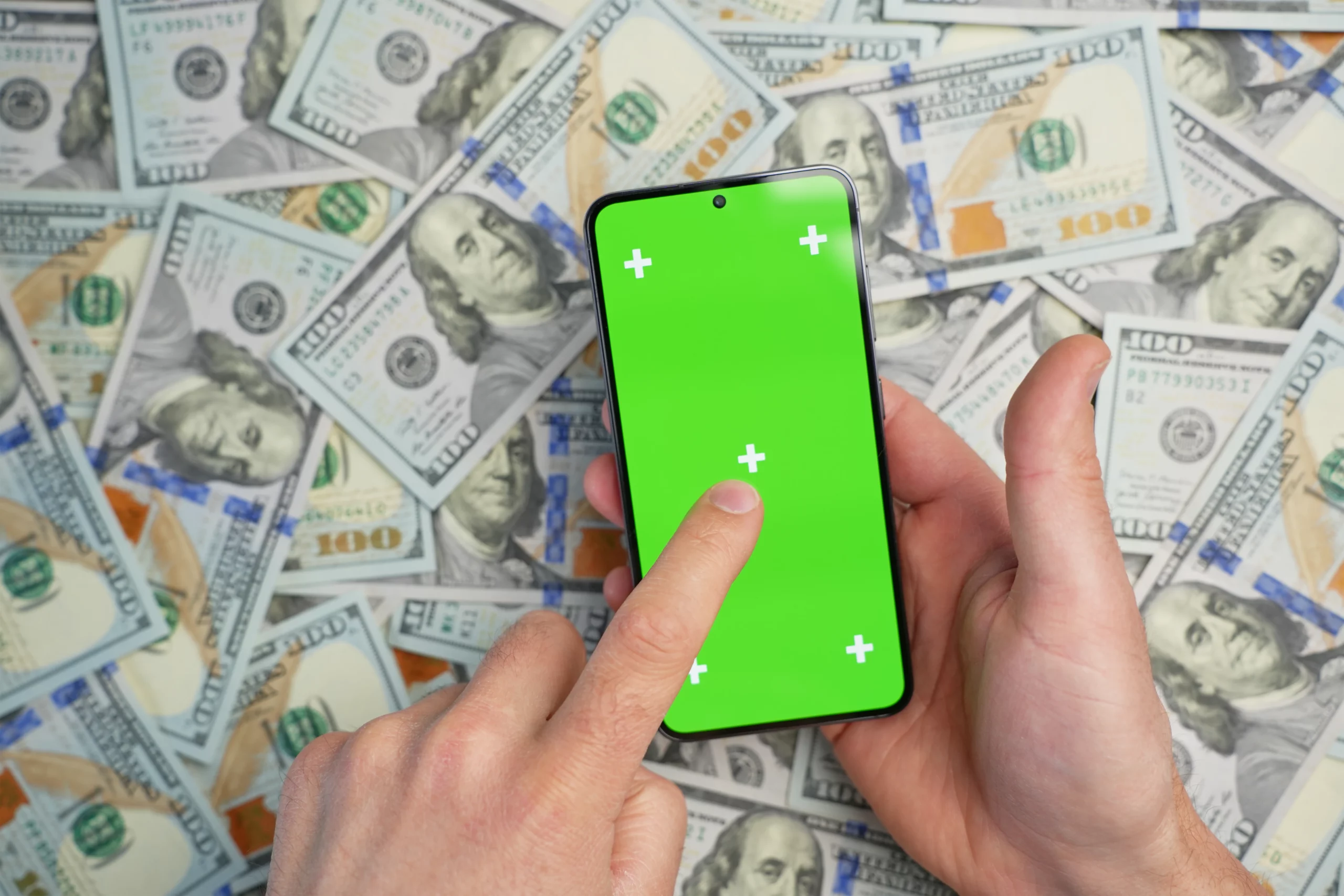 Hands holding a smartphone over U.S. dollar bills, illustrating questions about whether Cash App accounts and funds should be disclosed during a bankruptcy filing.